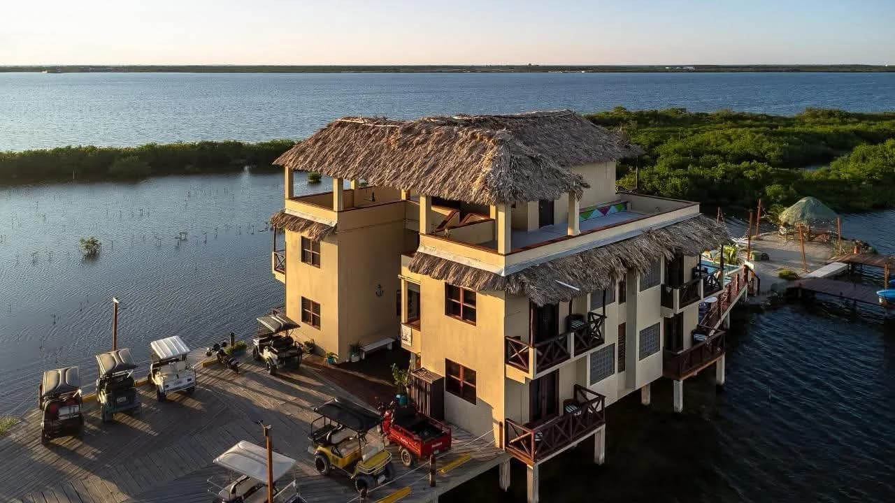 Lina Point's thatched-roof main building on the water at golden hour, golf carts parked on the dock.