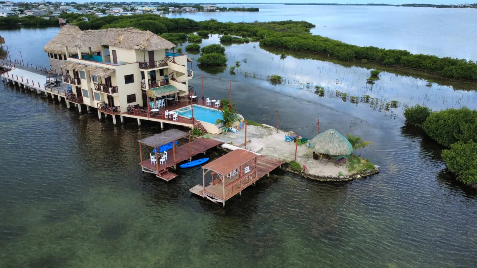 Aerial of Lina Point's overwater hotel with its pool, two dock gazebos and a palm-thatch palapa on the sandbar.